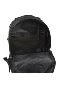 Interior de mochila negra con un compartimento con cremallera, que presenta un bolsillo de malla, textura de tela suave y forro con patrón de logo.