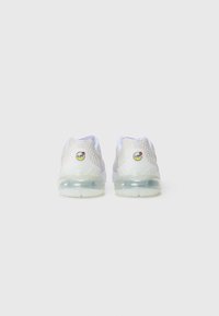 Une paire de sneakers Nike Air Max blanches montrées de l'arrière, avec des semelles à coussin d'air transparentes et des panneaux de talon texturés.