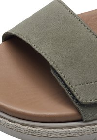 Sandalia de ante verde con una tira ancha, superficie texturizada y una plantilla suave de color marrón claro. Presenta una suela gris claro con costuras decorativas.