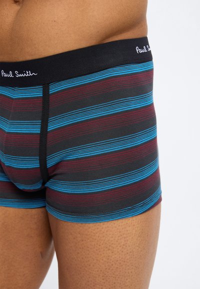 Ανδρικός κορμός που φοράει μποξεράκια με ρίγες σε μπλε, βουργουνδί και μαύρο οριζόντιες γραμμές και μαύρη ζώνη μέσης με λευκή επιγραφή "Paul Smith".