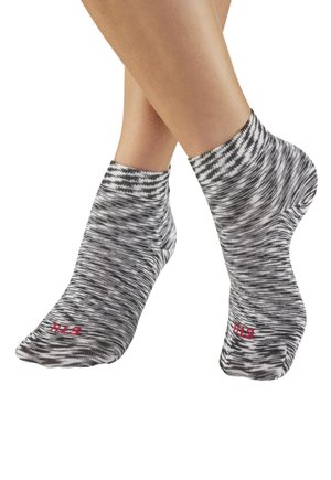 Feet wearing black and white marled ankle socks with red size markings on toes against a white background.