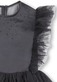 Robe noire avec un corsage en satin et des manches bouffantes en tulle, décorée de sequins dispersés. Jupe évasée avec un bord en tulle superposé.