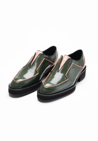 Groene lakleren schoenen met een unieke V-snede, roze accenten en een dikke zwarte platformzool. Gladde textuur en glanzende afwerking.