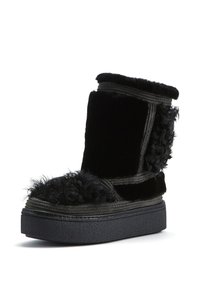 Stivale foderato in pelliccia nera con una tomaia texture, caratterizzato da una suola platform voluminosa e dettagli di cucitura a contrasto. Finitura morbida e soffice.