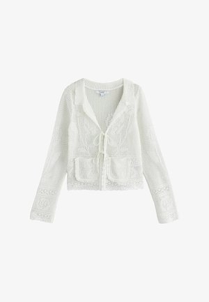 Baltas atviras megvąstas ilgomis rankovėmis kardiganas su gėlių raštais, dviem priekinėmis kišenėmis, banguotais kraštais ir surišamais priekiniais užsegimais.