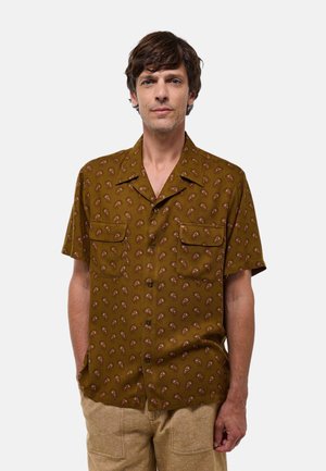 Chemise marron à manches courtes avec un motif paisley répétitif, dotée de deux poches poitrine et d'une coupe décontractée. Tissu texturé.