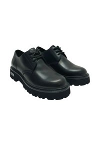 Ett paio di scarpe nere in pelle con lacci, suole spesse e scanalate e tacco basso, inclinate leggermente verso destra su uno sfondo bianco.