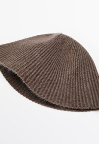 Berretto a costine marrone realizzato in morbida lana, con forma curva e superficie texturizzata. Nessun hardware o motivo visibile.