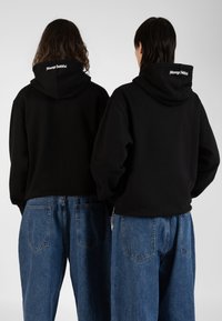 Black hooded sweatshirts with a relaxed fit, worn with loose blue jeans. The sweatshirts feature "Always Faithful" text on the back.