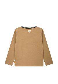Langärmliges Hemd aus beigem Baumwollstoff mit Rundhalsausschnitt und schwarzem Streifendetail. Mit einem Bären-Patch auf der Rückseite und geradem Saum.