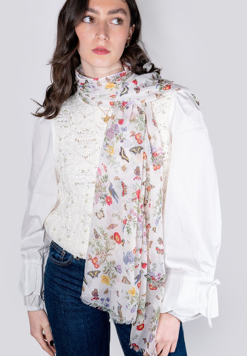 Bufanda floral ligera con un fondo blanco decorado con coloridas flores y mariposas, con bordes con flecos.