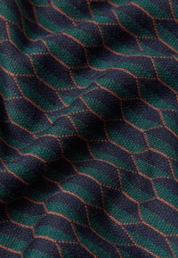 Gewebter Stoff mit einem geometrischen Diamantmuster in Grün und Marineblau, umrandet von orangen Nähten, die eine strukturierte Oberfläche schaffen.