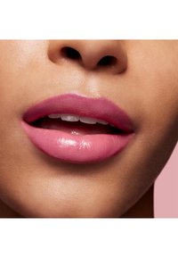 Close-up van lippen met een gradient van roze tinten, mat aan de buitenranden en glanzend in het midden, tegen een warme huidtint achtergrond.
