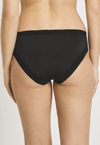 Black high-waisted panties made of smooth fabric, featuring a scalloped lace trim along the waistband and leg openings.