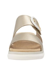 Gold metallic sandals with two wide straps and a circular white buckle. Soft beige insole and white rubber sole, minimalistic design.