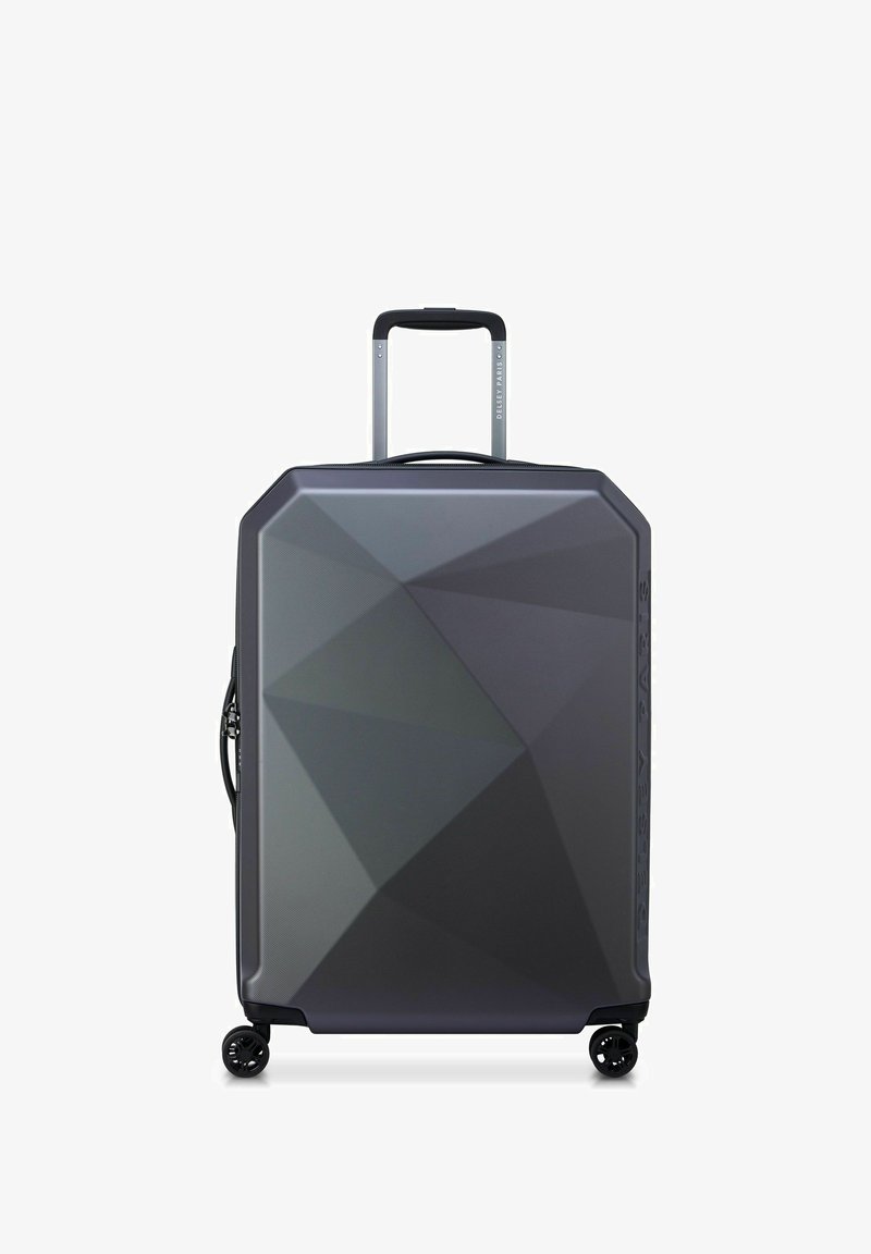 Valigia rigida grigia scura con motivi geometrici, quattro ruote girevoli, manico telescopico esteso e maniglia laterale.