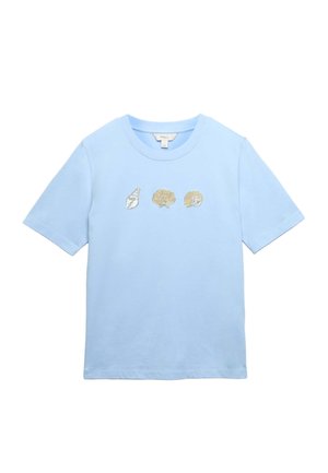 Lyseblå kortærmet t-shirt med rund hals og tre broderede muslingeskaller i sølv- og gyldne toner på tværs af brystet.
