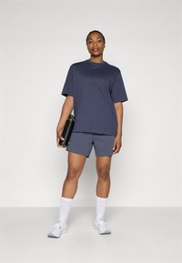 Navy short-sleeve t-shirt and matching shorts made of soft fabric; paired with white knee-high socks and gray athletic shoes. Holds a black water bottle.