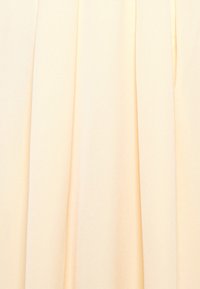 Hento keltainen kangas, pehmeällä ja sileällä tekstuurilla, jossa pystysuuntaisia laskoksia rakenteen ja liikkeen luomiseksi. Ei muita kuvioita tai metalliosia näkyvissä.