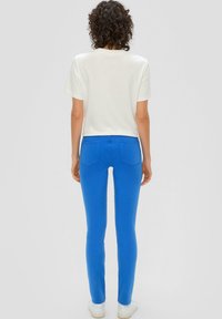 Blauwe skinny jeans met een gladde textuur en vijfzakken ontwerp, gecombineerd met een plain wit T-shirt met korte mouwen en witte sneakers.