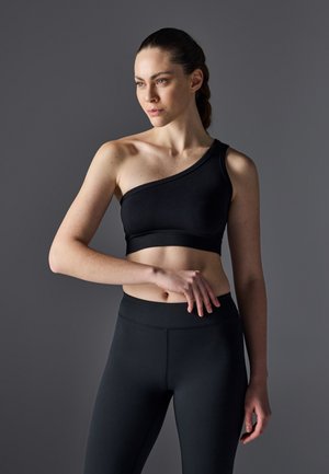 Black one-shoulder crop top made of smooth, stretchy fabric, paired with high-waisted black leggings. Simple design with no visible patterns.