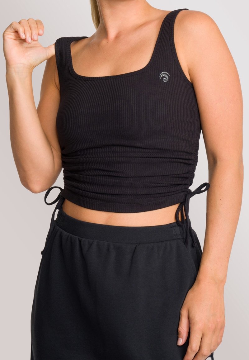 Svart kort croppad linne med ribbad textur, fyrkantig halsringning och sidobanddetaljer, kombinerat med svarta byxor med dragsko.