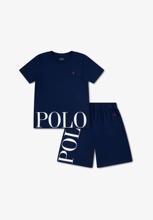 Tengerészkék pamut póló piros logóval és fehér "POLO" blokkbetűs felirattal az alján. Hozzáillő tengerészkék rövidnadrággal párosítva, hasonló mintával.
