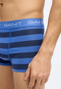 Modro-teget boksarice z raztegljivim pasom z blagovno znamko. Mehka tkanina in oprijet dizajn. Vidni šivi.