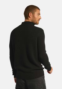 Czarny sweter z wysokim kołnierzem, z ściągaczem na dole i przy rękawach, z teksturowanym wzorem dzianiny. Zaprojektowany w luźnym kroju.