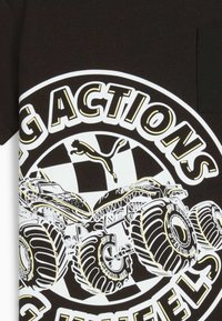 Schwarzes T-Shirt mit einer weißen und gelben Grafik von Monstertrucks, schachbrettartigem Hintergrund und teilweise fettem Text "Große Aktionen", der sie umgibt.