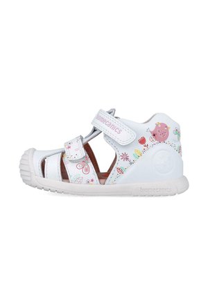 Sandalia blanca para niños con estampado floral en rosa y verde, diseño abierto, correa de Velcro y suela de goma con punta redondeada.