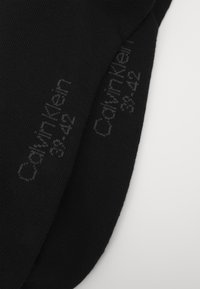Calze nere con texture a coste, dotate di un discreto marchio grigio di Calvin Klein. Progettate per adattarsi alle taglie 38-42.