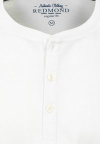 Witte katoen henley shirt met een ronde hals, drie-knopen placket en subtiele tekstuur. Label toont "REDMOND" en maat "M."