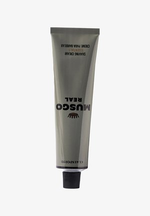 Tube der Musgo Real Rasiercreme mit schwarzem Deckel und grauer Verpackung, beschriftet mit "Creme para Barbear Essentials."