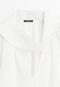 Witte blouse met een brede kraag en een zichtbaar merkje "Massimo Dutti" genaaid aan de binnenkant van de halslijn.
