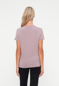 Kortsleeve topp i lys mauve med rund hals og en glatt tekstur. Ren design uten synlige mønstre eller detaljer.