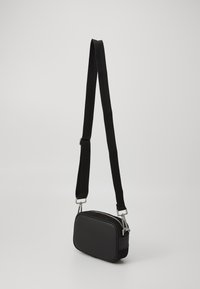 Borsa a tracolla nera con forma rettangolare, realizzata in materiale liscio, dotata di accessori in argento e una tracolla regolabile.