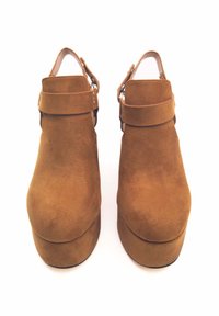 Scarpe platform in suede marrone con punta rotonda e cinturino alla caviglia. Presentano una superficie liscia e un tacco spesso per un'altezza maggiore.