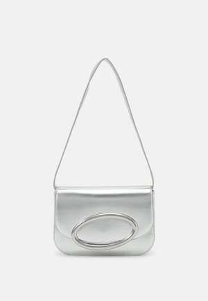 Srebrna metaliczna torebka na ramię z cienkim paskiem i dużą owalną klamrą na przedniej klapie na jednolitym tle.
