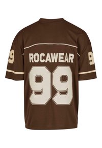 Barna, rövid ujjú mez, fehér díszítéssel, a hátán nagy "ROCAWEAR" felirattal a "99" szám fölött, figyelemre méltó betűtípussal.