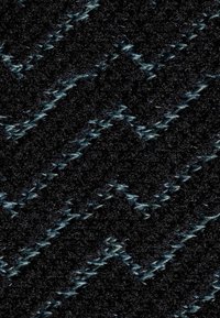 Tessuto con uno sfondo nero texturizzato e un motivo a zigzag in tonalità di grigio e blu. La superficie appare morbida con un effetto scintillante.