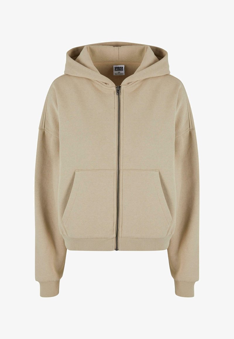 Beidzīga krēmkrāsas kapuci ar rāvējslēdzēju, kas aprīkota ar šņorēm, priekšējām kabatām, ribuotām piedurknēm un mīkstu tekstūru, izgatavota no ērtas kokvilnas materiāla.