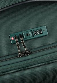 Maleta verde oscuro con un acabado texturizado, que cuenta con un candado de combinación TSA y cremalleras metálicas. Acentuada por un tirador de cremallera con logo.