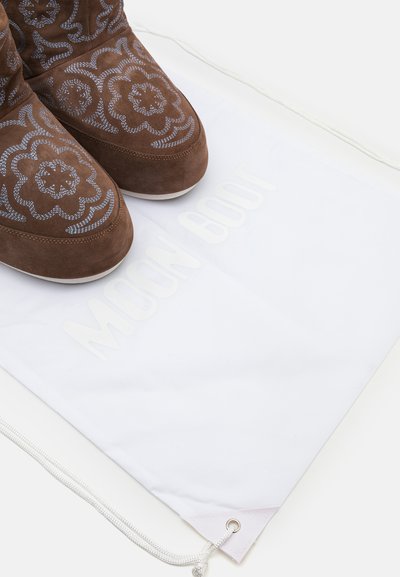 Brown suede Moon Boot featuring floral embroidery, paired with a white drawstring bag displaying the brand name in light gray.