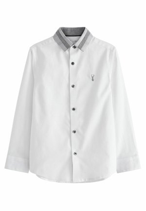 Chemise blanche à manches longues avec boutons noirs, col à carreaux gris et petite tête de cerf brodée sur la poitrine gauche.