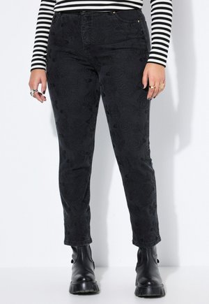 Sorte slim-fit bukser med subtilt blomsterprint, båret med sorte støvler og en sort-hvid stribet langærmet top fra taljen og ned.