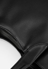 Zwarte faux leren handtas met een gestructureerd oppervlak, voorzien van een ritssluiting en elegante, gebogen handvatten. Duurzaam en minimalistisch ontwerp.