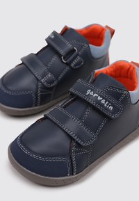 Zapatos de cuero azul con correas de velcro, acentos grises y forro naranja. Punta redondeada y suela de goma con detalles de costura. Nombre de la marca visible.