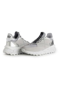 Zapatillas deportivas grises con una parte superior de malla texturizada, detalles de ante, un talón plateado y una suela blanca moteada. Los cordones presentan una marca en negro.