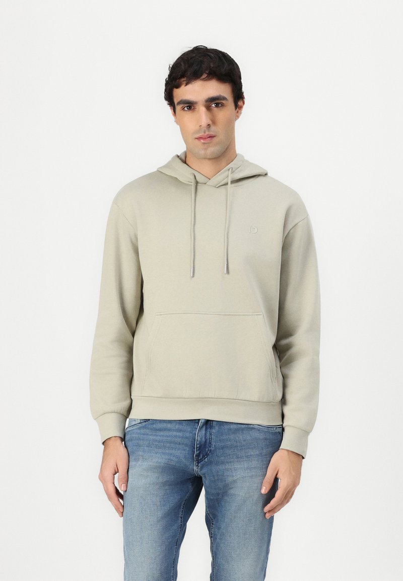 Camisola capuz cinza-claro com bolso frontal, capuz com cordão e logótipo bordado no peito. Usada com jeans azuis. Textura suave.